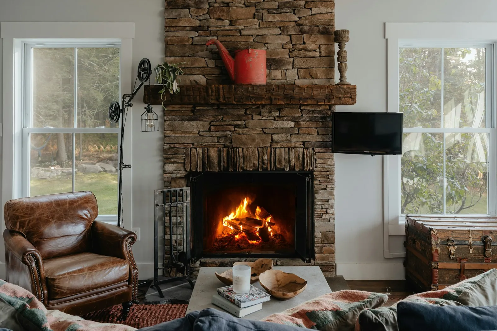 Fire burning in a stacked-stone fireplace in a bright living room