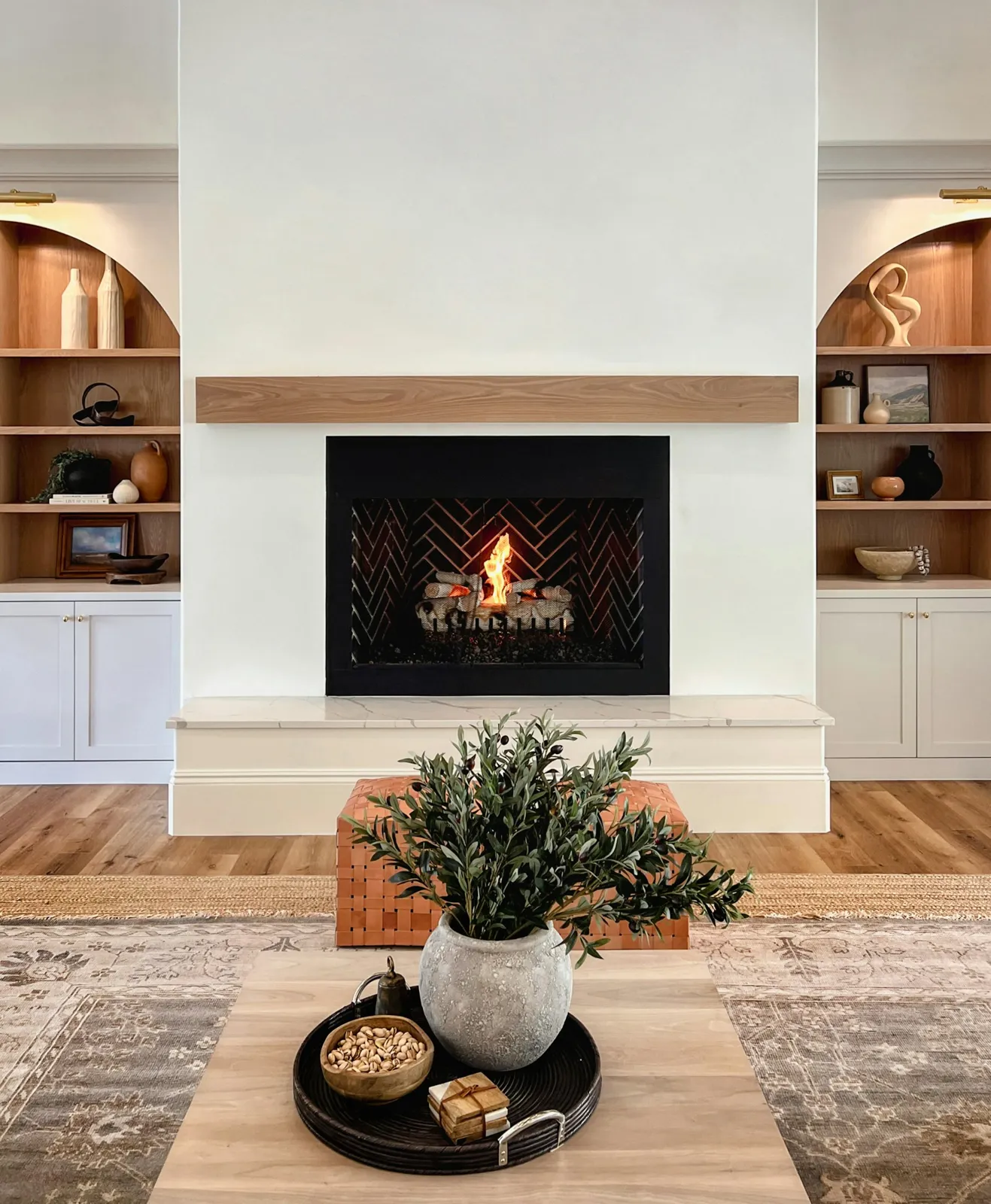 Gas fireplace with a wood mantel between white built-in shelves