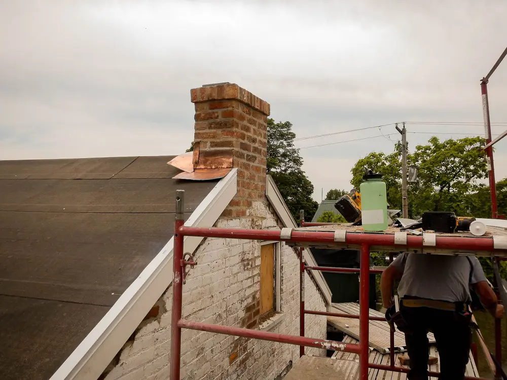 Mason installing copper flashing at a chimney